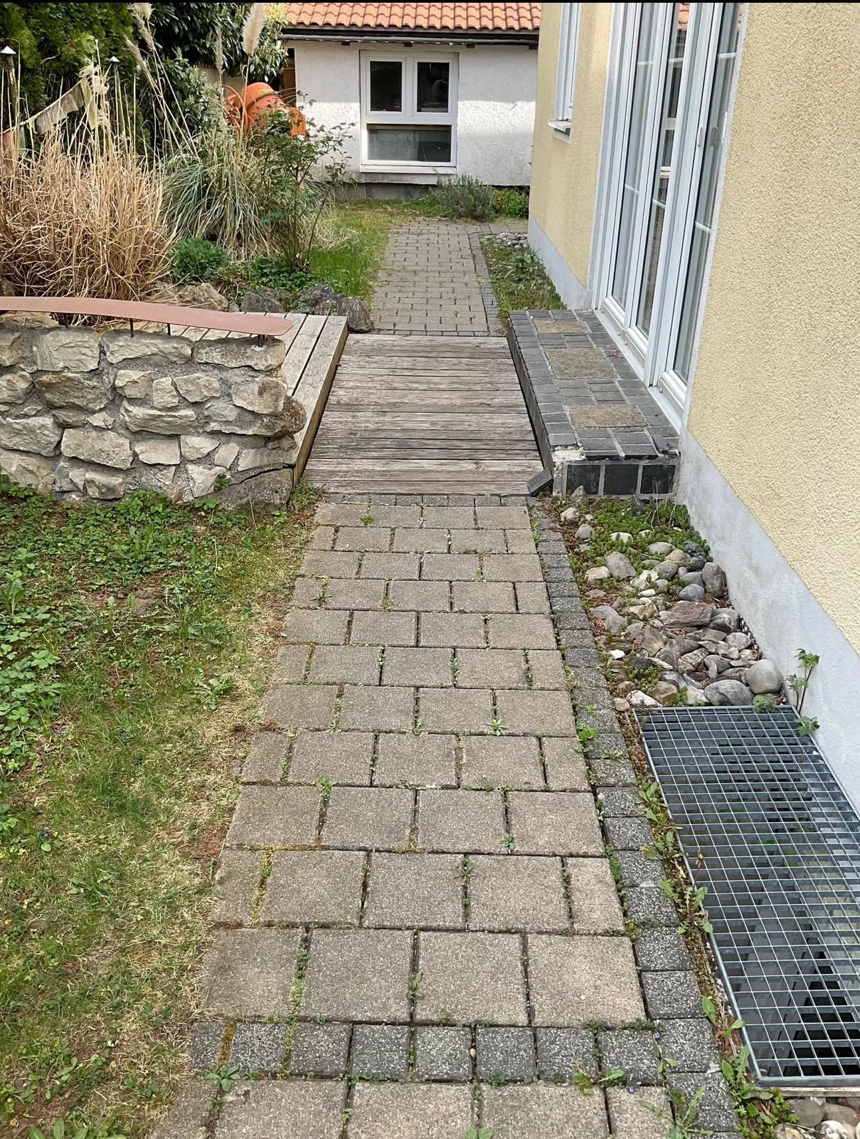 Gepflasterter Gartenweg vor der Pflege mit Bewuchs in den Fugen